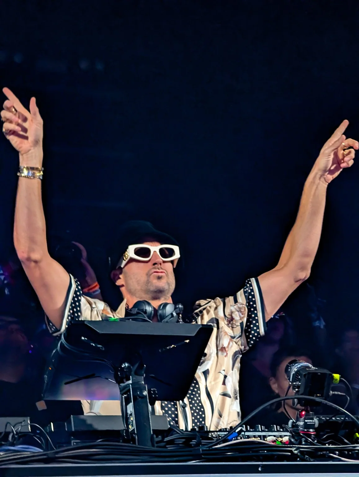 DJ raising both arms during a club set